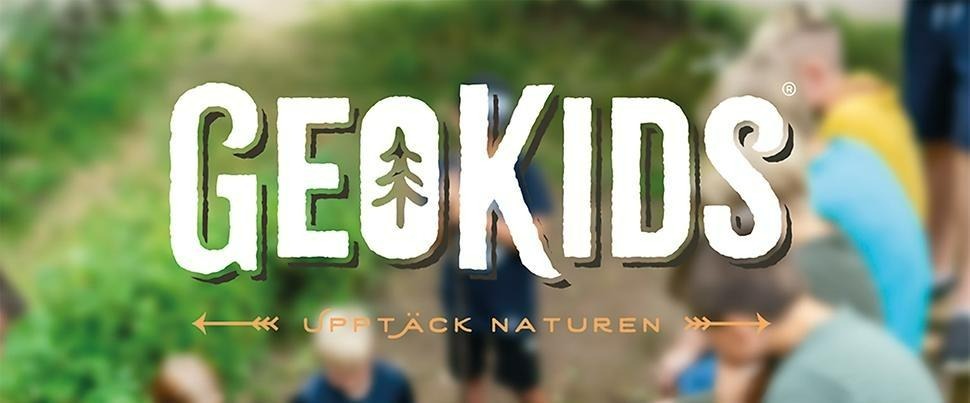foto av barn i en skog. Loggan för lägret, texten GEOKIDS ligger mitt på bilden.